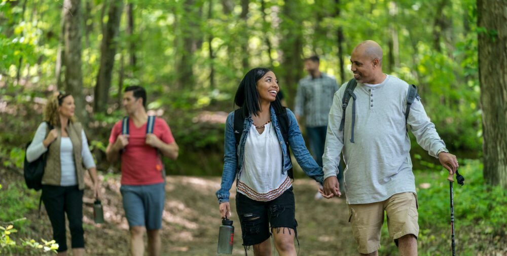An image of two couples hiking through green trees at WinShape.