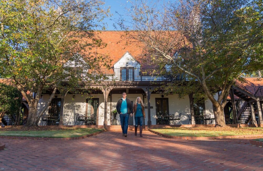An image of a married couple walking out of WinShape's Normandy Inn while holding hands and smiling