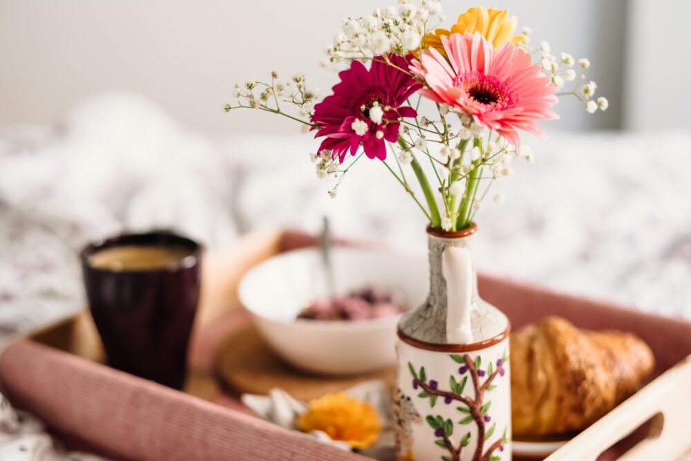 A couple is having breakfast in bed, one of our 15 Valentine's Day date ideas
