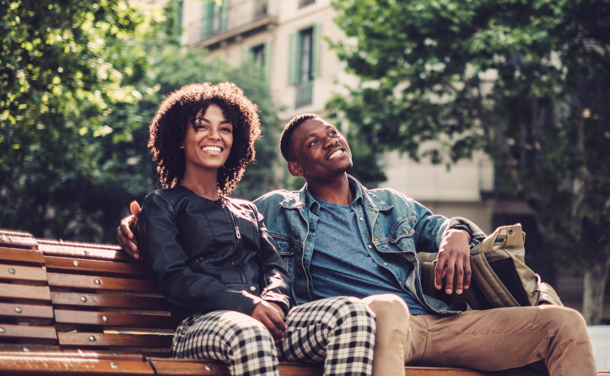 a happy young couple sitting on a bench staring off into the distance wondering about opposite-sex friendships in marriage