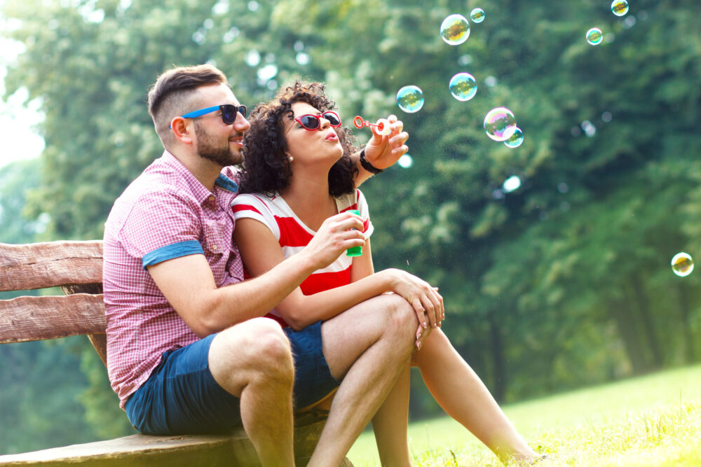 a young married couple enjoying one of our spring date ideas, blowing bubbles and becoming kids again