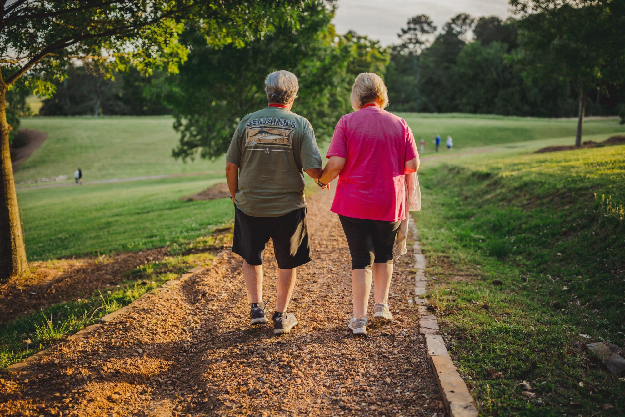 A couple holding hands while walking through a green field at a WinShape Marriage Retreat.