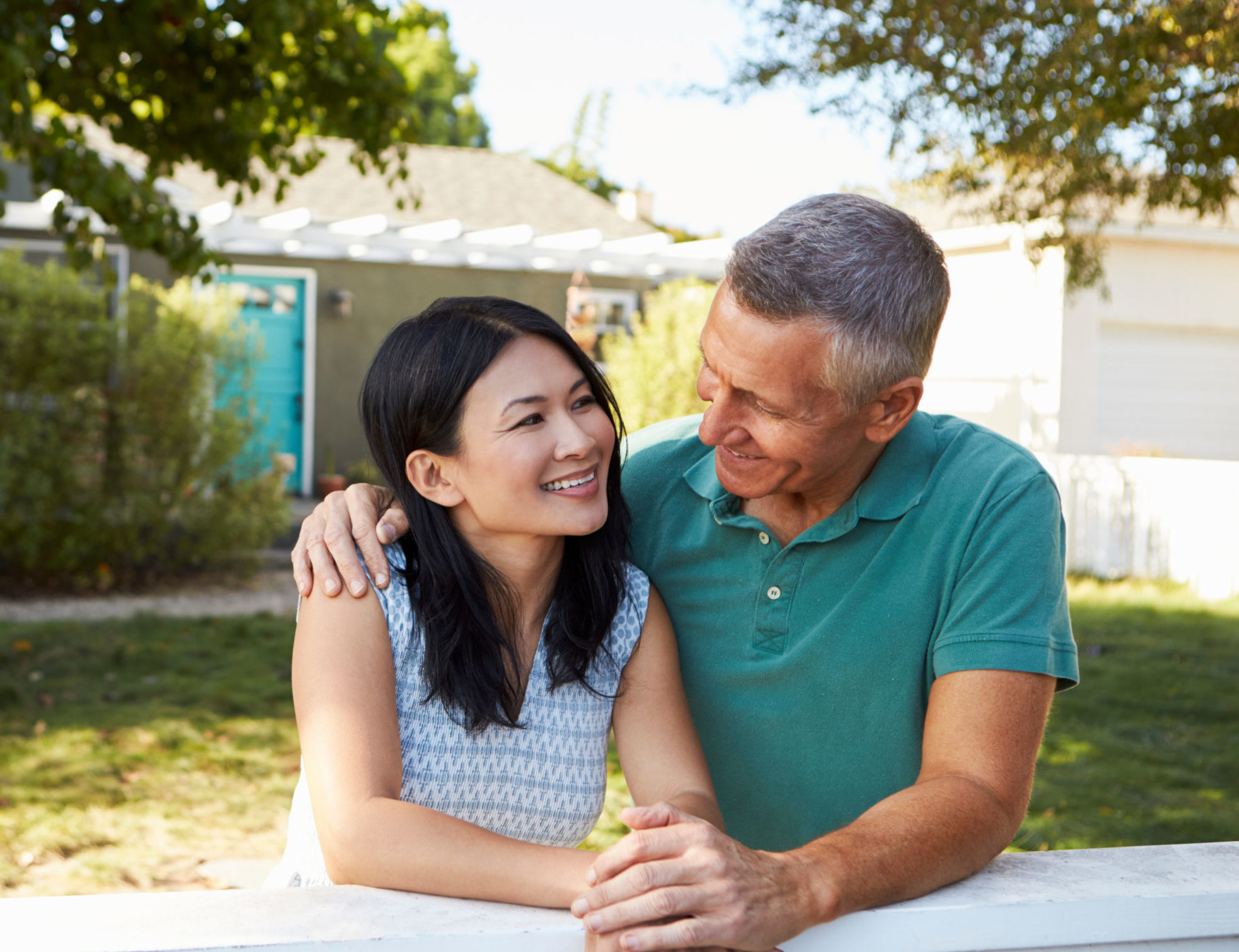 Empty Nest Couple smiling while leaning against a fence