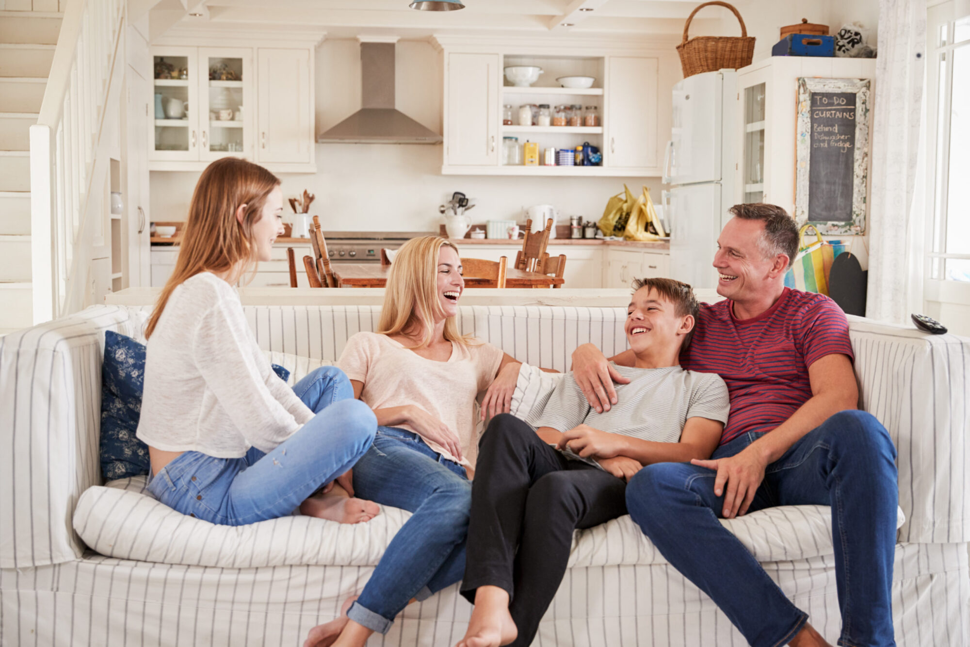 Middle-aged married couple with teenage children sitting on the couch using free printable family conversation starters