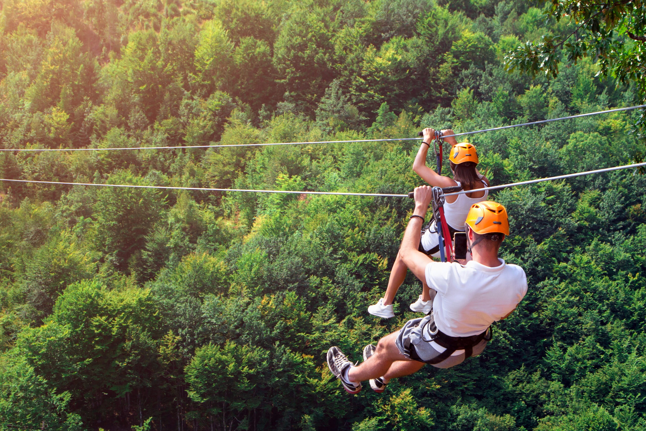 A young married couple zip-lining through trees one of our summer date ideas
