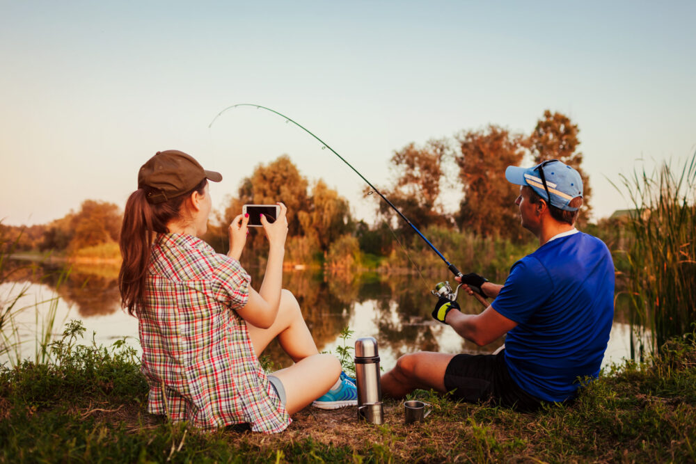 Young married couple enjoying fishing at a lake one of our summer date ideas