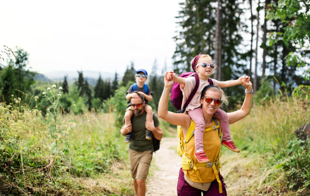 Young married couple with children enjoying a summer date hiking outside on a trail one of our summer date ideas