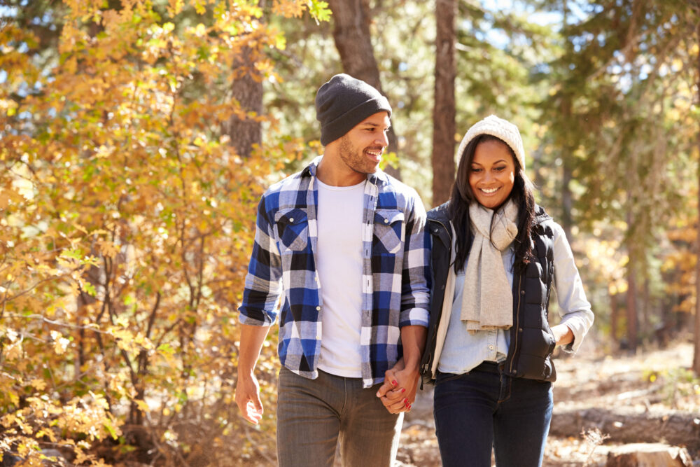 Young married couple enjoying a fall date hiking together among fall foliage
