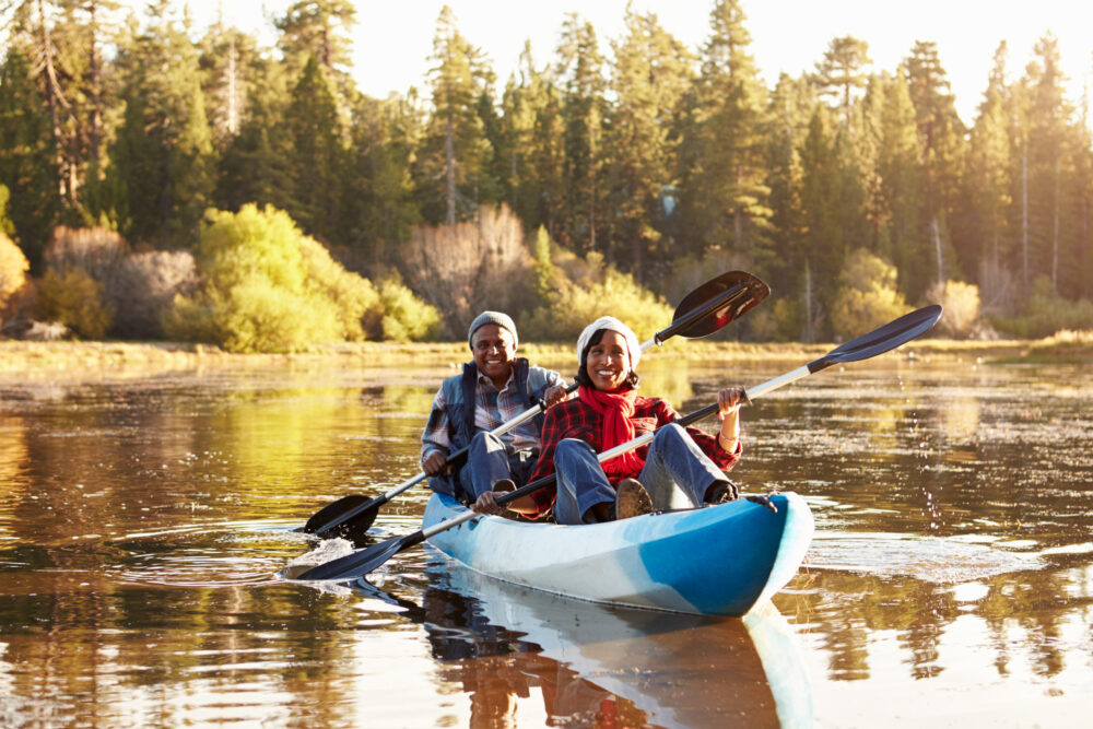 Older married couple kayaking among autumn leaves during a fall date