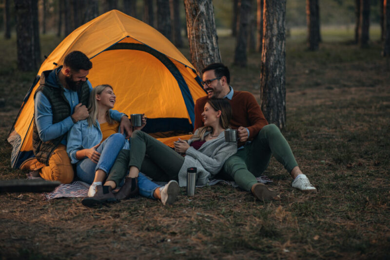 Young married couples on a double date in the fall time camping and laughing together