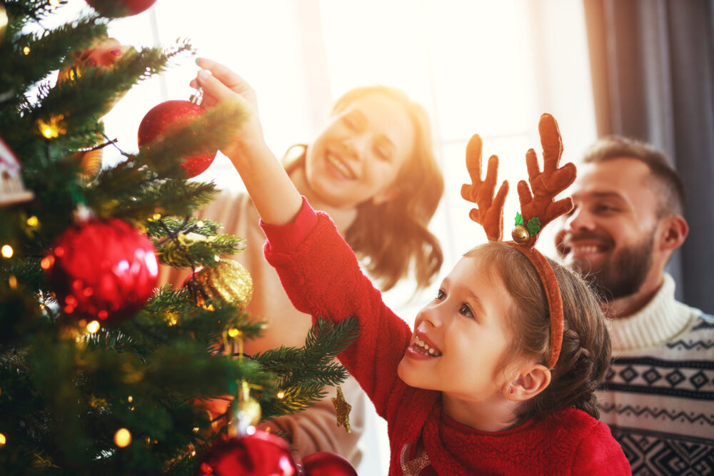 Young married couple with their child participating in a Christmas date by decorating for Christmas