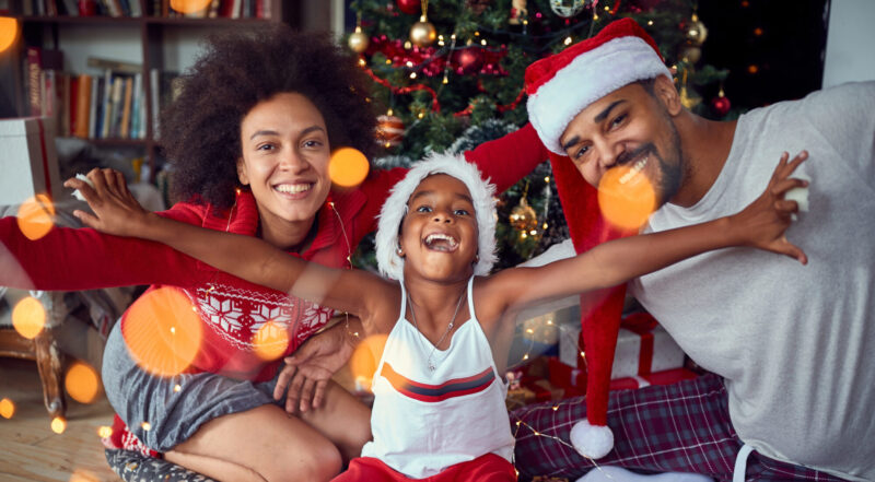 Younger married couple with a child celebrating Christmas with a Christmas date wrapping presents