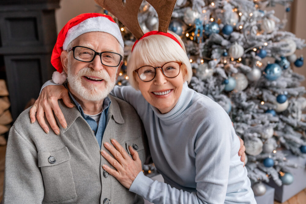 Older married couple enjoying a Christmas date together having a Christmas photoshoot in front of the tree