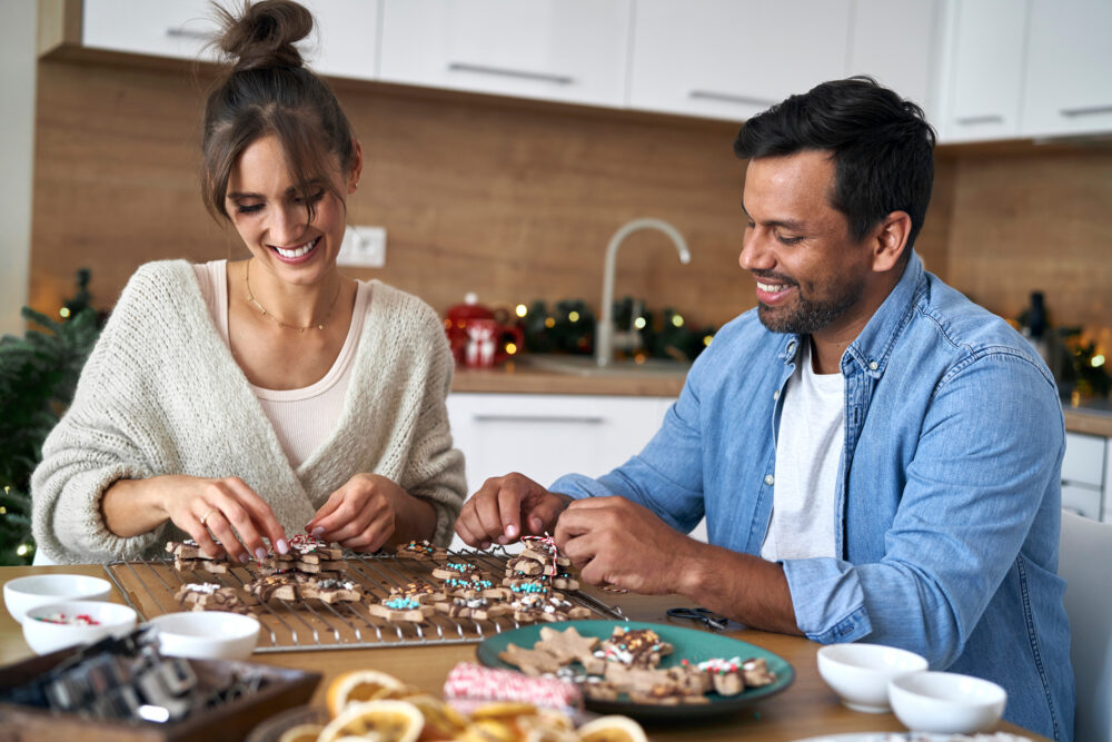 Young married couple enjoying a Christmas date together baking and decorating holiday cookies