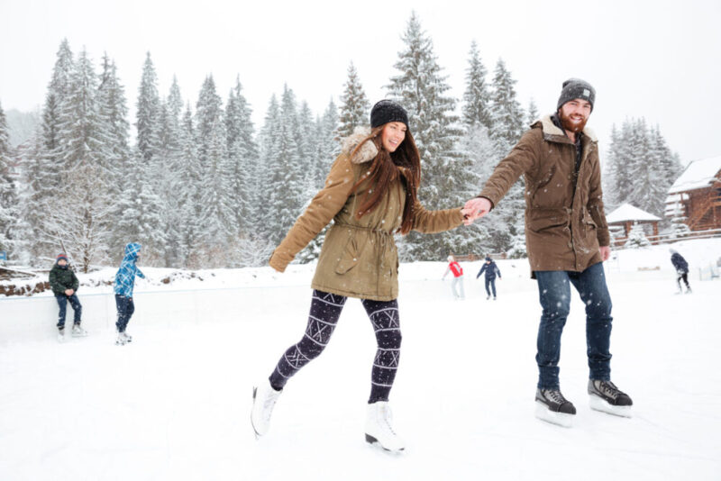 Young married couple ice skating together, one of our winter date ideas