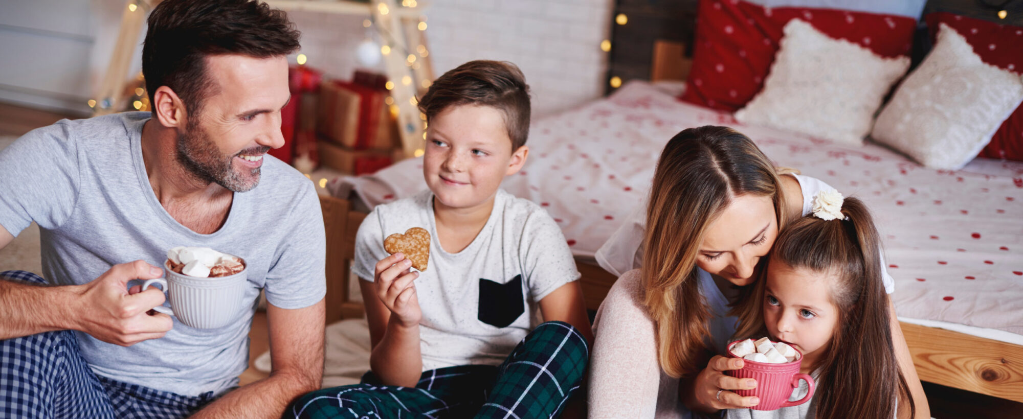 Married couple with children enjoy hot cocoa at their indoor picnic, a winter date idea