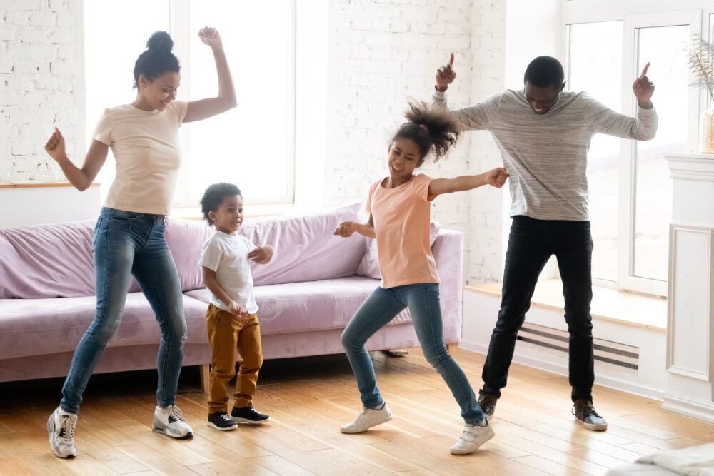 Married family with small children celebrating each other by having a dance party in their living room, practicing teamwork in their marriage