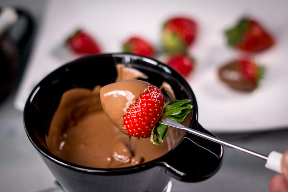 Young married couple choosing to partake in a unique date idea by making homemade chocolate fondue.