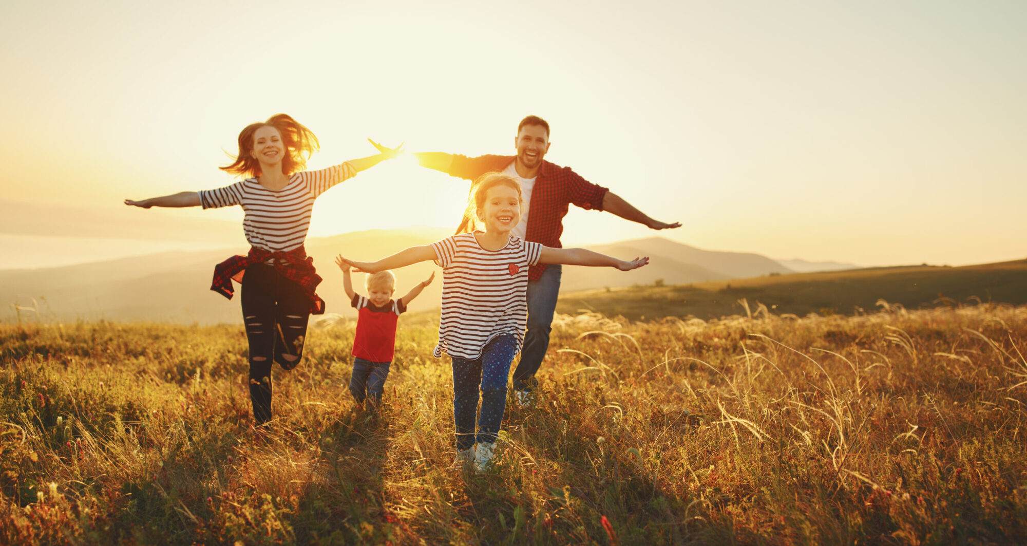 Family experiencing sunset together; parents are curious about how to explain God to a child, and they're helping their children to understand God in nature