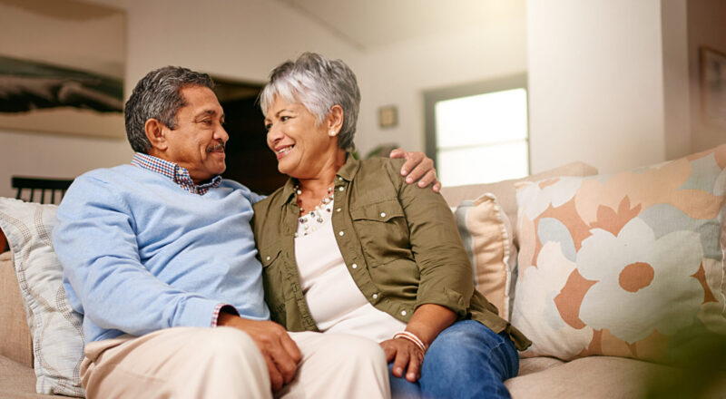 Older married couple at home on their couch working through figuring out what is the empty-nest syndrome together