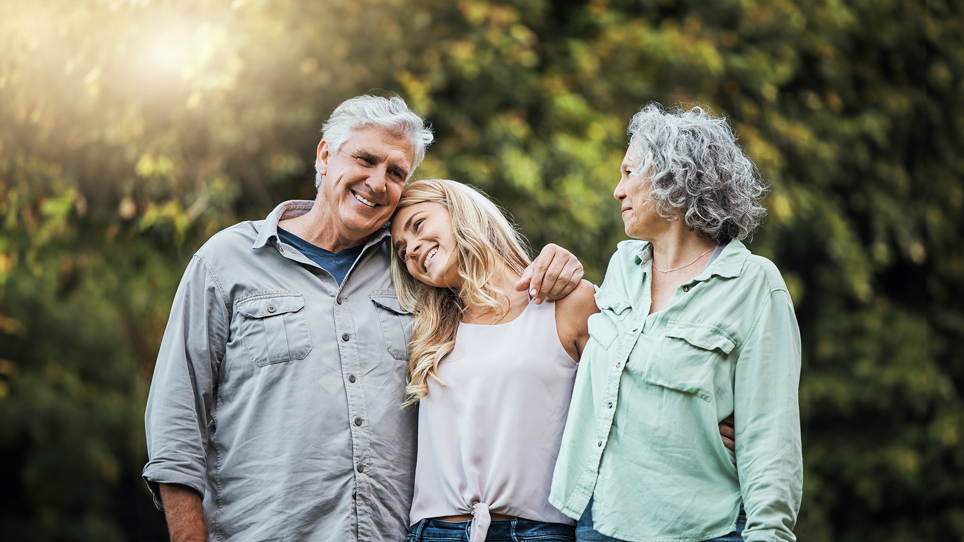 an image of an empty nest couple hugging their young adult daughter