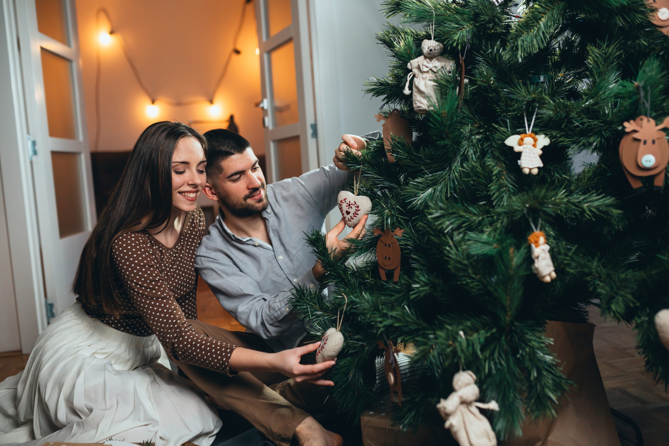 younger married couple decorating their christmas tree, one of our 80 date ideas for couples, christmas date ideas