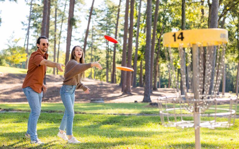 young married couple playing disc golf, one of our fun active date ideas