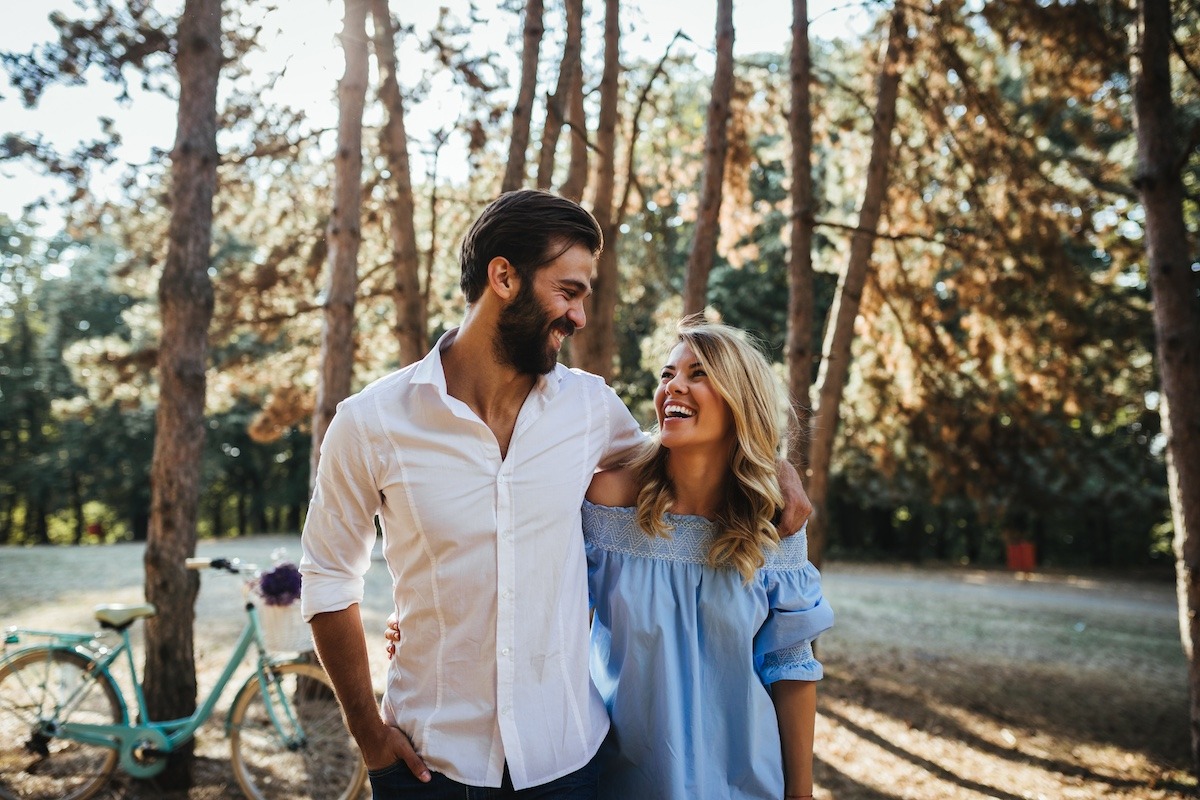 Happy couple cuddling while walking in the woods.