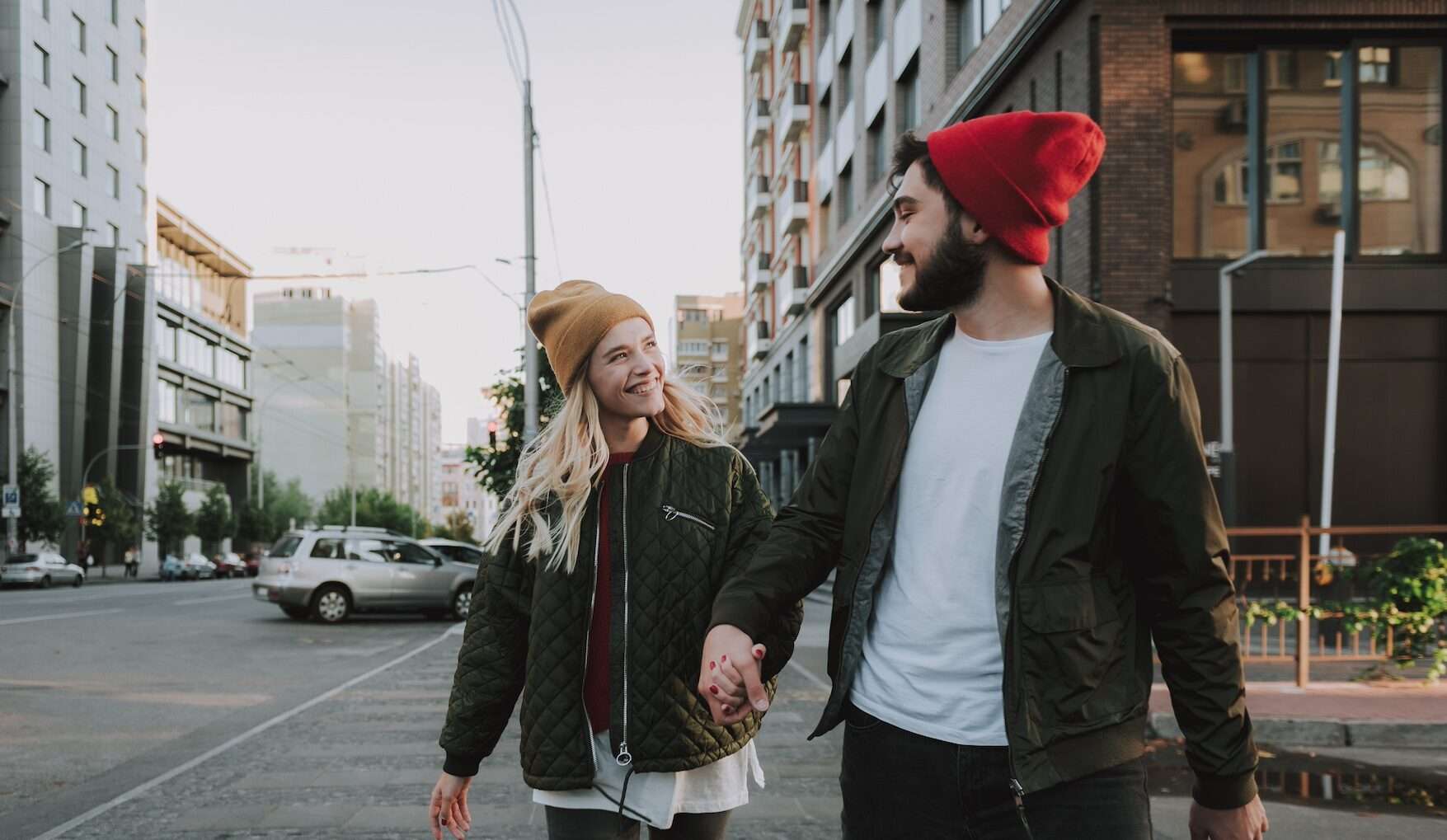 Happy young couple holding hands while walking on the street talking through date ideas