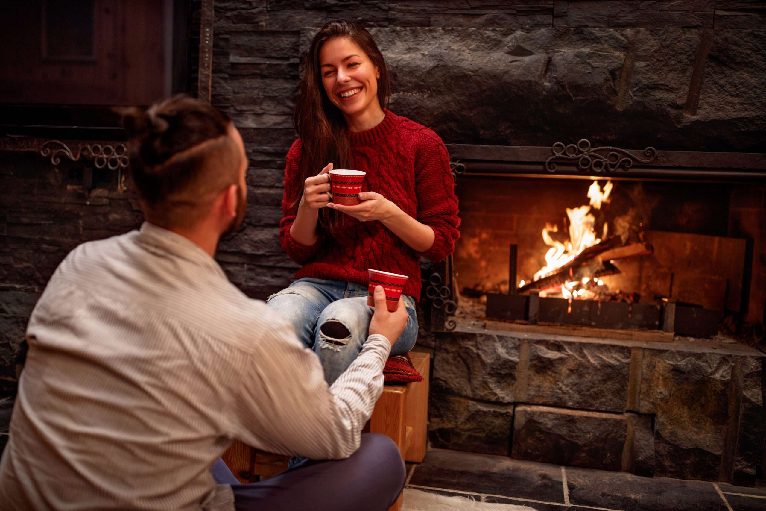 Younger married couple sitting in front of the fireplace talking, a Christmas date idea