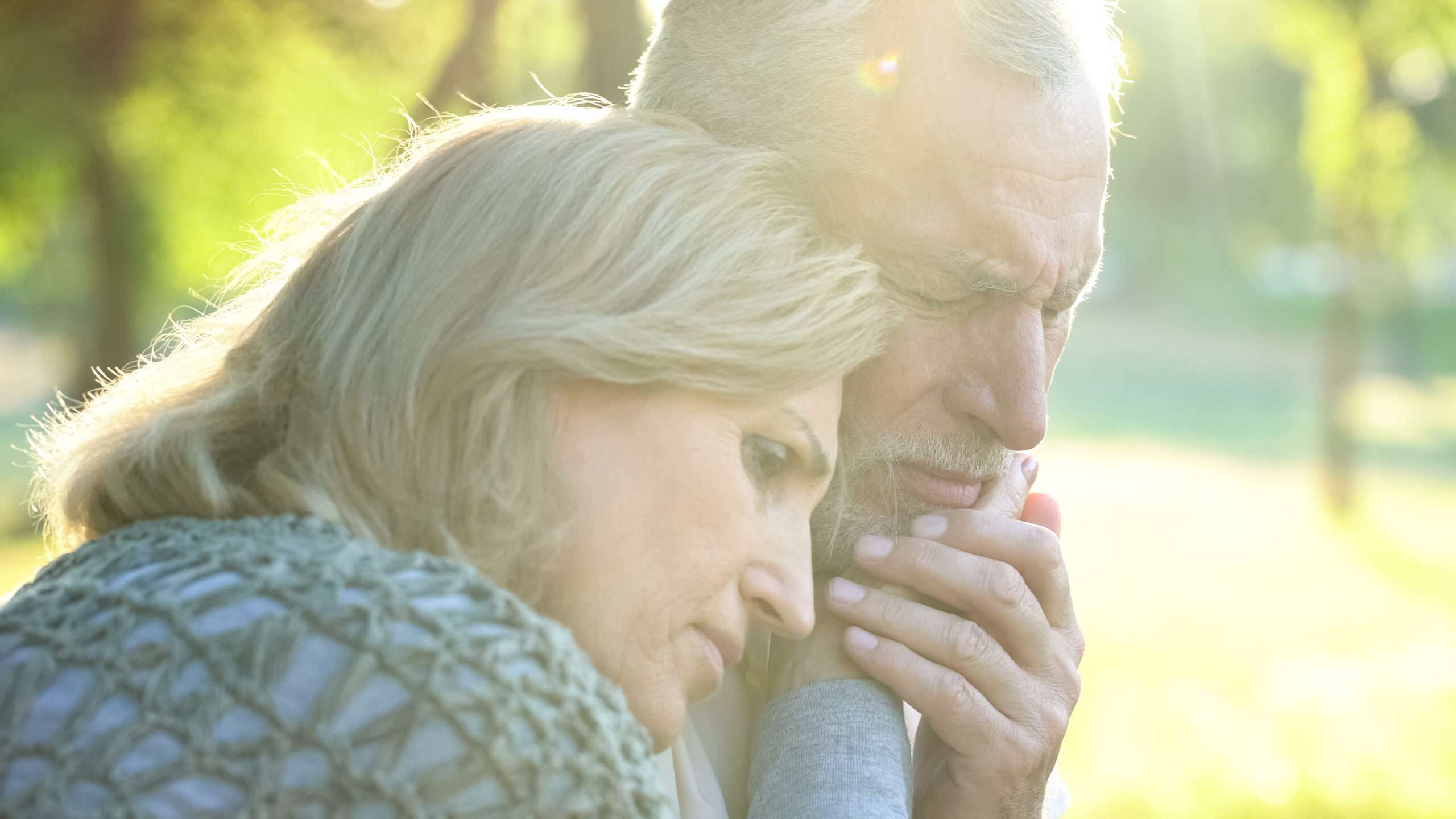 Husband and wife embracing solemnly, wife encouraging her husband with the squeeze of a shoulder, a simple way for how to help a grieving spouse