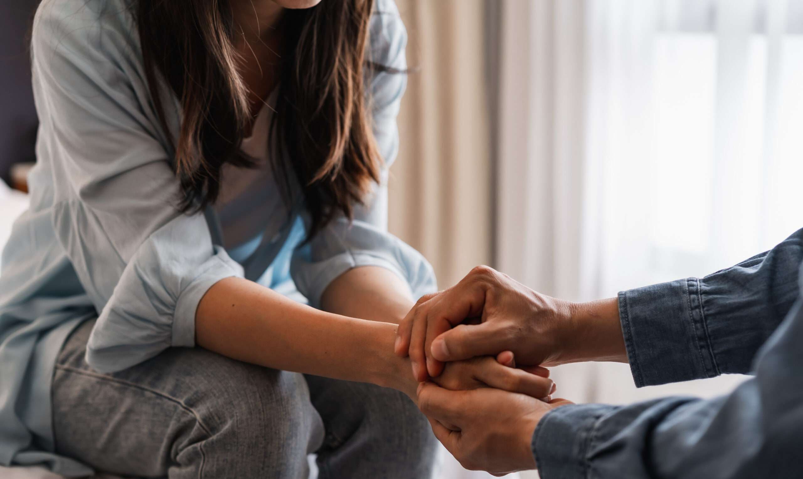 Husband and wife holding hands, husband encouraging his wife with the squeeze of a hand, a simple way for how to help a grieving spouse