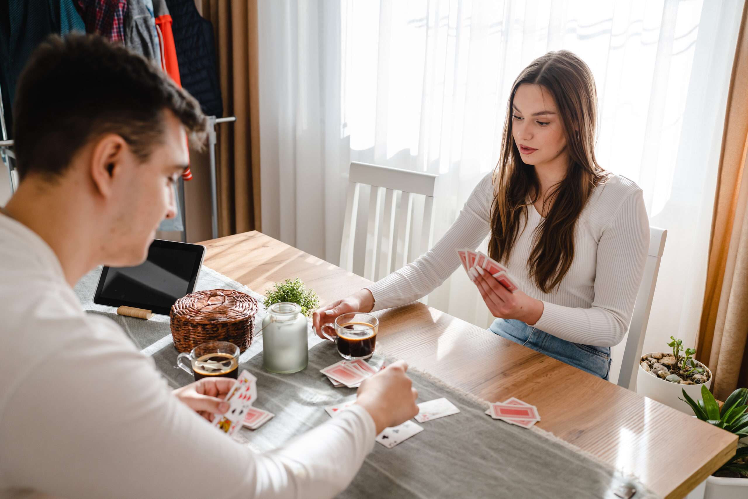 Younger married couple playing a card game; keeping their marriage healthy by knowing good games to play with your spouse
